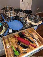 Full view of bakeware and pots on countertop plus drawer with baking utensils and tools.