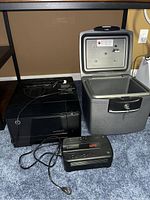Overall view of HP color printer, security safe, and Back-UPS 350 power backup seen on carpet with cords and keys.