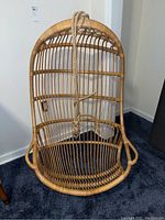 Full front view of hanging bamboo chair showing curved seat and back with attached rope.