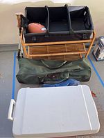 Overview of all items including shoe rack, football, hiking poles, cooler and green carrying bag.