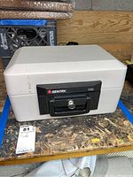 Front view showing Sentry 1150 safe with key lock on black handle and minor surface marks on beige body.