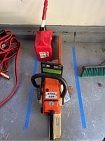 Stihl chainsaw on floor with red fuel can and jumper cables visible