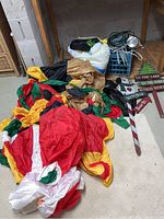 Photo of large deflated nylon Christmas inflatables in red, yellow, green, and black colors, alongside wooden Christmas-themed yard signs with directional text.