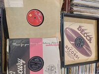 Photo showing various vintage 78 RPM records from different labels including Columbia, Decca, Victor, and Mercury, some framed and some in original sleeves.