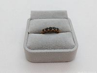 Front view of ring showing five dark faceted stones in single row