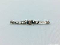 Front view of brooch showing openwork filigree design and center stones