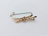 Front and angle views of 14k yellow gold bar brooch with five pearls and one seed pearl, showing safety chain and clasp.