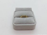 Front view of the ring displayed in grey velour ring box showing overall appearance.