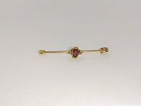 Front view of the gold bar brooch showing the garnet and side stones.