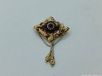 Front view of brooch showing central garnet and pearl cluster with tassel chain