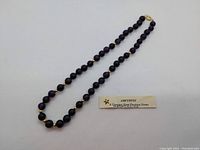 Full view of 16-inch amethyst bead necklace with alternating gold spacer beads laid out straight.