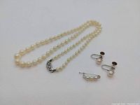 Full set of costume pearl jewelry items displayed on white background: necklace, pin, and pair of earrings visible.