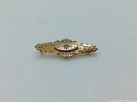 Full front view of bar brooch showing overall shape, filigree and central diamond