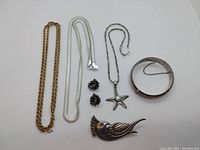 Full lot of silver jewelry items: three necklaces, earrings, bird brooch, cuff bracelet
