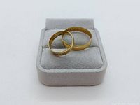 Two gold bands displayed on gray ring holder
