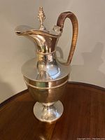 Front and side views of the silver plate wine ewer showcasing its vasiform body and wrapped handle.