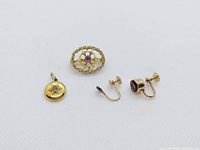 All four pieces together: circular pendant with diamond, oval brooch with pearl and amethyst, two single yellow gold earrings (one missing a stone)
