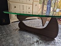 Side view showing thick clear glass top and dark wood sculptural base