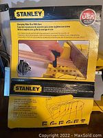 Close-up of the packaging showing Stanley clamping mitre box made in USA, with diagram and description of product functionality.