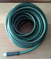 Coiled green NeverKink garden hose with black rubber connector