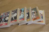 Stacked baseball card sets with visible top cards showing player names and teams.