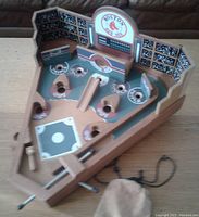 Front view of the wooden Boston Red Sox baseball pinball game showing playing field, scoring holes, scoreboard and small pouch with steel balls