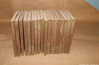 Photo showing all 18 small hardcover books from the front with spines aligned, revealing wear and water stains on covers.