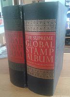 Two black hardcover Supreme Global Stamp Albums with gold and red spine text, standing side by side.