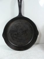 Top view of an 11-inch black cast iron frying pan with two pouring spouts and a handle with a hanging hole.