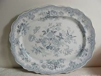 Full view of the antique ironstone platter with pale grey blue floral and bird decoration and scalloped edge.