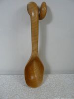 Full view of hand-carved wooden spoon showing deep bowl and curled handle design