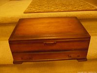 Closed wooden flatware box with smooth polished wood surface and small handles on drawer and lid