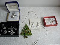 Full lot overview showing all jewelry pieces including snowman brooch, Christmas tree brooch, snowflake necklace, and snowman earrings