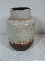 Front view of small ceramic vase showing textured lava glaze with cream and brown colors