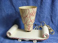 Front angled view of the ceramic lamp showing the shape and pattern of the shade and the scroll-like base detailing.