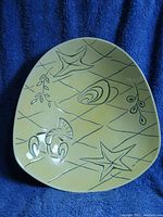 Full view of the triangular ceramic serving dish with embossed seafood and starfish designs on a green background.