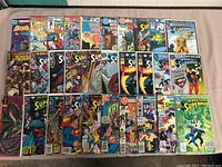 Wide angle of multiple comic books including Superman, Spider-Man, and Batman titles arranged on a surface.