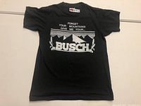 Full view of the black vintage Busch T-shirt laid flat showing front design and condition