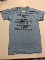 Full view of the blue vintage T-shirt laid flat showing front graphic and text