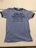 Full view of blue vintage ringer T-shirt with text print 'OLD TRUCKERS NEVER DIE They just blow a shift. CACHE CREEK HUSKY'.