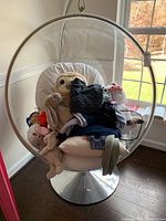 Overall front view of clear acrylic bubble chair on chrome stand with white cushion and non-included items inside