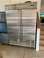 Full front view of two-door stainless steel refrigerator showing exterior and casters