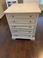 Front view showing five drawers with metal knobs and white paint finish.
