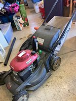 Front left view of mower showing deck, engine, handle and grass catcher attached