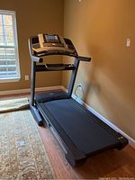 Full view of treadmill showing running deck, frame, and console