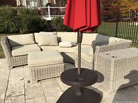 Overall view of three-piece curved wicker sectional with cushions, ottoman and side table