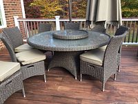 Full view of round wicker patio table with glass top and removable lazy Susan insert