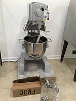 Front view of mixer with bowl installed and attachments displayed