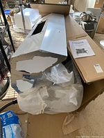 Titan rotisserie grill components still in original packaging with visible metal body and installation booklet on top of the box.