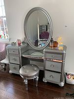 Full view of silver vanity desk with oval mirror and tufted stool